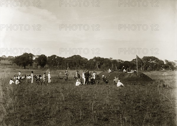 Firing point annual meeting. A group of European men accompanied by their African servants, take practice shots from the top of a mound of earth constructed as a firing point. The original caption suggests this was an 'annual meeting'. Entebbe, Uganda, circa 1930. Entebbe, Central (Uganda), Uganda, Eastern Africa, Africa.