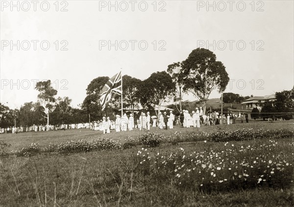 The King's birthday reception. A union jack flag, surrounded by men in white uniforms, flies high at a reception held in honour of King George VI's birthday. Uganda, circa December 1936. Uganda, Eastern Africa, Africa.