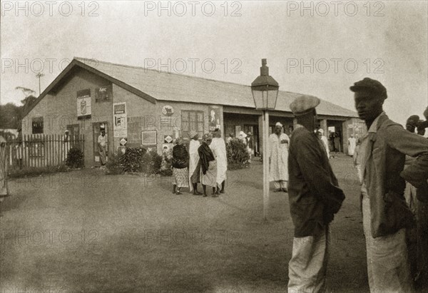 Jos railway station. African men and women mill around on the street outside Jos railway station. Jos, Nigeria, circa 1932. Jos, Plateau (Nigeria), Nigeria, Western Africa, Africa.