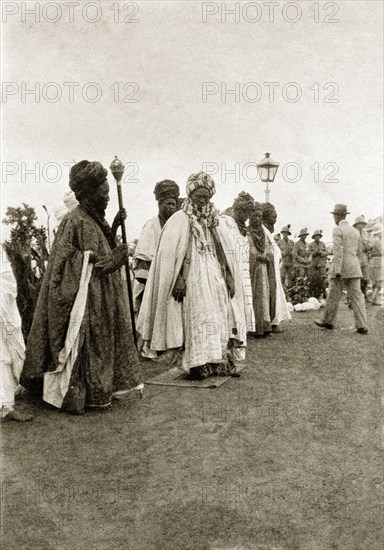 The Emir of Zaria. The Emir of Zaria, dressed in fine robes, holds a staff as he parades with a group of his supporters. Zaria, Nigeria, circa 1932. Zaria, Kaduna, Nigeria, Western Africa, Africa.