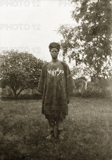 Nigerian policeman. Portrait of a Nigerian policeman dressed in a robe with white writing on his chest. Nigeria, circa 1932. Nigeria, Western Africa, Africa.