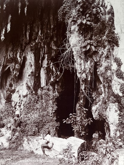 Entrance to the Batu Caves. Two Tamil men sit outside the entrance to the Batu caves in the jungle. Near Kuala Lumpur, British Malaya (Malaysia), circa 1900., Kuala Lumpur, Malaysia, South East Asia, Asia.