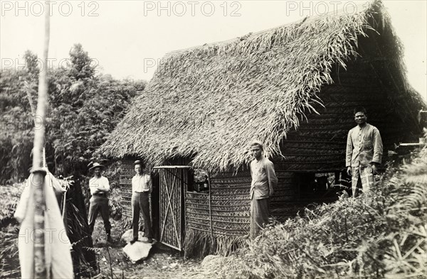 British surveying team at Bukit Asa. British surveyors and their Malay assistants at a thatched survey hut at Bukit Asa. The team are engaged in surveying the Bernam base line extension, the original caption mentioning an 'astronomical point'. Selangor, British Malaya (Malaysia), circa 1900., Selangor, Malaysia, South East Asia, Asia.