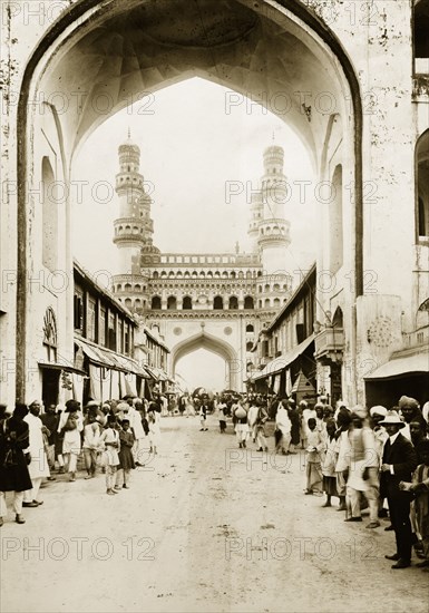 The Char Minar in Hyderabad. Pedestrians line a street running towards the Char Minar. Hyderabad, India, circa 1905. Hyderabad, Andhra Pradesh, India, Southern Asia, Asia.