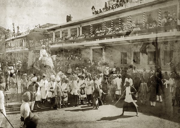 Religious parade, India. Europeans line the upper balconies of a city street to watch a religious parade, possibly a procession to celebrate Muharram, the first month of the Islamic lunar calendar. India, circa 1900. India, Southern Asia, Asia.
