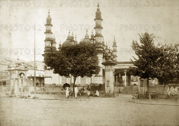 Mosque on Dhurumtollah Street. People sit in the shade of trees outside a mosque decorated with domes and minarets on Dhurumtollah Street. Calcutta (Kolkata), India, circa 1890. Kolkata, West Bengal, India, Southern Asia, Asia.