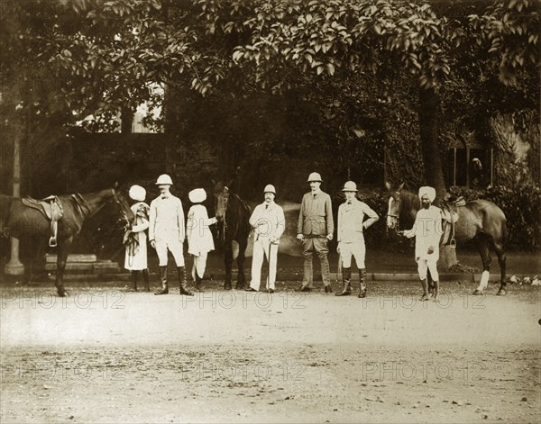 British men with Indian servants. Four British men pose for the camera, their Indian servants waiting with saddled horses behind them. Calcutta (Kolkata), India, August 1895. Kolkata, West Bengal, India, Southern Asia, Asia.