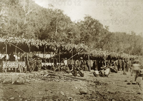 Chin tribesmen, Burma (Myanmar). A group of Chin tribesmen from the Chin Hills crouch beneath a makeshift, grass-roofed shelter. Rakhine, Burma (Myanmar), January 1897., Rakhine, Burma (Myanmar), South East Asia, Asia.