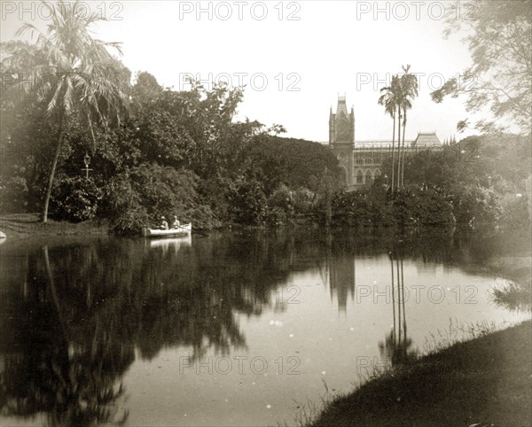 Afloat in the Eden Gardens. A couple in a rowing boat glide across the still waters of a pool in the Eden Gardens, the High Court building visible in the distance. Calcutta (Kolkata), India, circa 1890. Kolkata, West Bengal, India, Southern Asia, Asia.