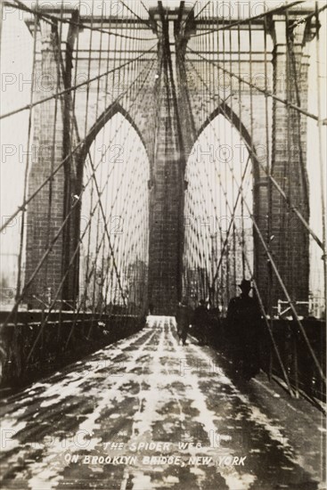 "The Spider Web on Brooklyn Bridge". View along the pedestrian path of Brooklyn Bridge. A printed caption terms this walkway "The Spider Web" in reference to the criss-cross steel-wire used in the bridge's construction. New York, United States of America, circa 1942. New York, New York, United States of America, North America, North America .