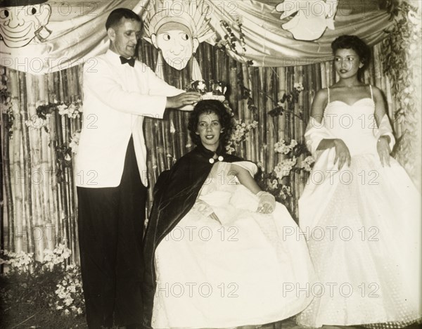 Wallace Macmillan crowns a Carnival Queen. Wallace Macmillan (1913-1992), the British colonial administrator of Grenada between 1951 and 1957, crowns a beauty pageant contestant, Wendy Lawrence, as Carnival Queen. Another contestant, Rose Lawrence, awaits her prize as runner-up. Grenada, 2 March 1957. Grenada, Caribbean, North America .