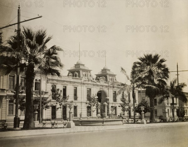 Municipal building in Lima, Peru. View across a street to a colonial-style municipal building in Lima. The two-storey building features a flat, balustraded roof with two square towers flanking an arched entrance. Lima, Peru, circa 1920. Lima, Lima Metropolitana, Peru, South America, South America .