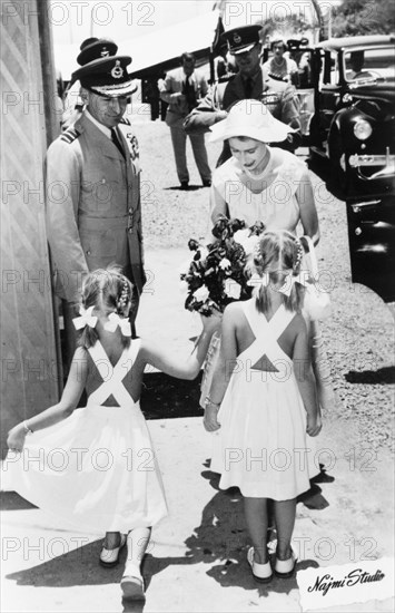 Queen Elizabeth II presented with flowers by two girls in Aden, 1954. Two young girls present a bouquet of flowers to Queen Elizabeth II, during her visit to Aden as part of a royal tour of the Commonwealth from November 1953 to May 1954. Aden, Yemen, 27 April 1954. Aden, Adan, Yemen, Middle East, Asia.