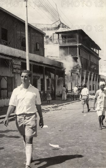 Row of shops destroyed during the riots in Aden, 1947. A European man walks past a row of shops in the Jewish quarter of Aden, which have been burnt and destroyed during the Arab riots that took place between 1-3 December 1947 in response to the United Nations Partition Plan for Palestine. Aden, Yemen, December 1947. Aden, Adan, Yemen, Middle East, Asia.