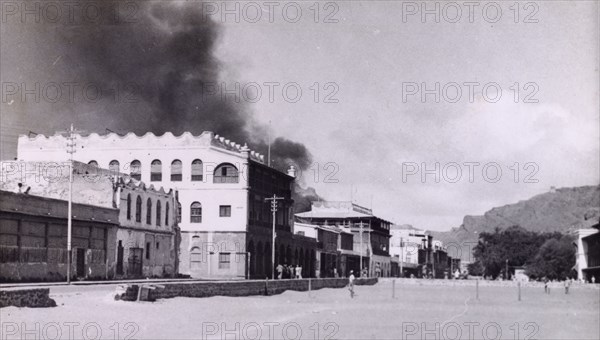Riot damage in Aden, 1947. A plume of black smoke rises from a building in the Jewish quarter of Aden, during the Arab riots that took place between 1-3 December 1947 in response to the United Nations Partition Plan for Palestine. Aden, Yemen, December 1947. Aden, Adan, Yemen, Middle East, Asia.
