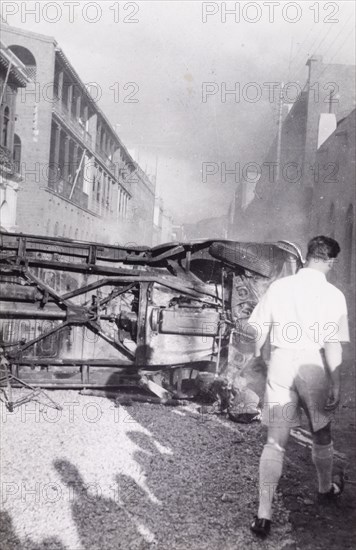 Aftermath of Arab riots in Aden, 1947. A European man walks around an upturned truck lying in the middle of a road in the Jewish quarter of Aden, after the Arab riots that took place between 1-3 December 1947 in response to the United Nations Partition Plan for Palestine. Aden, Yemen, December 1947. Aden, Adan, Yemen, Middle East, Asia.