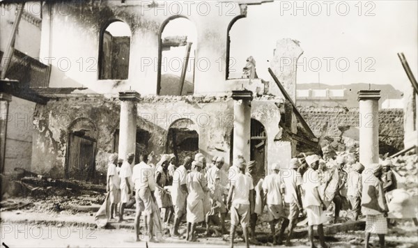Aftermath of Arab riots in Aden, 1947. A crowd of men gather outside a gutted building in the Jewish quarter of Aden, after the Arab riots that took place between 1-3 December 1947 in response to the United Nations Partition Plan for Palestine. Aden, Yemen, December 1947. Aden, Adan, Yemen, Middle East, Asia.
