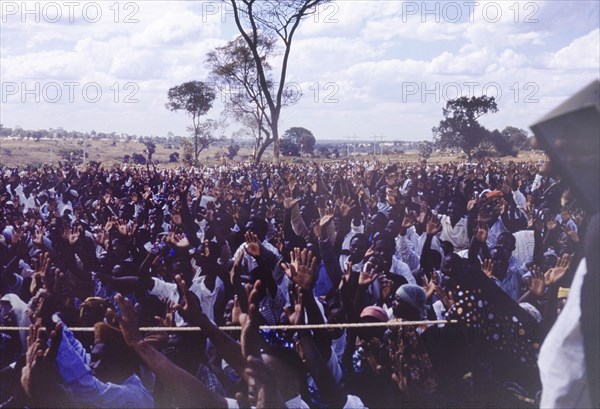 Crowds at an United National Independence Party rally. Supporters at the United National Independence Party's political rally acclaim the leaders by raising both their hands with their palms facing forward. Kitwe, Northern Rhodesia (Zambia), circa 1962. Nkana-Kitwe, Copperbelt, Zambia, Southern Africa, Africa.