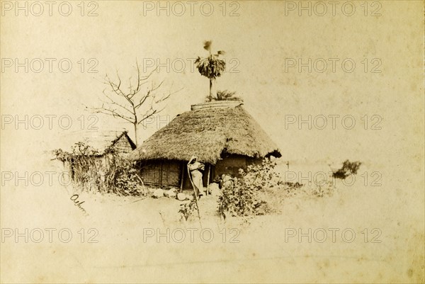 Village dwelling, Indian. An Indian woman stands on the path outside a thatched village dwelling. India, circa 1890. India, Southern Asia, Asia.