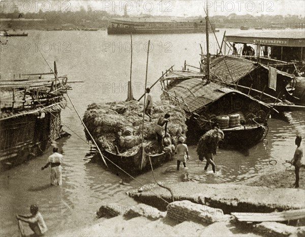 Loading jute at Serajgunge. Indian workers load bales of jute onto a cargo boat at the riverside harbour of Serajgunge. The jute mill at Serajgunge was one of several that sprang up in the West Bengal area during the late 1800s as the jute industry began to take off in India. Serajgunge, India, circa 1890. Serajgunge, West Bengal, India, Southern Asia, Asia.