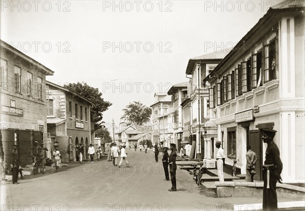 Custom Street, Lagos. A view of Custom Street, dominated by European-based companies. Uniformed African police officers are stationed at intervals along the road. Lagos, Nigeria, circa 1925. Lagos, Lagos, Nigeria, Western Africa, Africa.