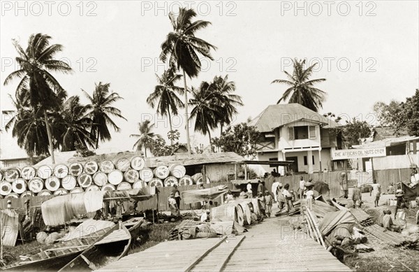 Palm oil storage yard. Barrels of palm oil wait to be collected by boat at a riverside storage yard belonging to the African Oil Nuts Company. Badagry, Lagos, Nigeria, 1924. Badagry, Lagos, Nigeria, Western Africa, Africa.