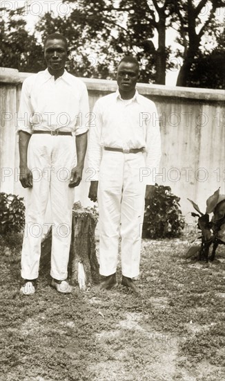 Domestic servants in a garden. Portrait of two male domestic servants, 'Joe' a cook and 'Sam' a steward, in a garden. Both men wear white shirts and trousers. Badagry, Nigeria, circa 1928. Badagry, Lagos, Nigeria, Western Africa, Africa.