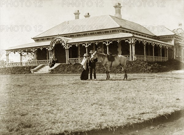House called 'Wyalla', Australia. A couple with a saddled horse stand on the lawn at 'Wyalla', a large single-storey colonial house with wide verandas and multiple chimneys. Toowoomba, Australia, circa 1905. Toowoomba, Queensland, Australia, Australia, Oceania.