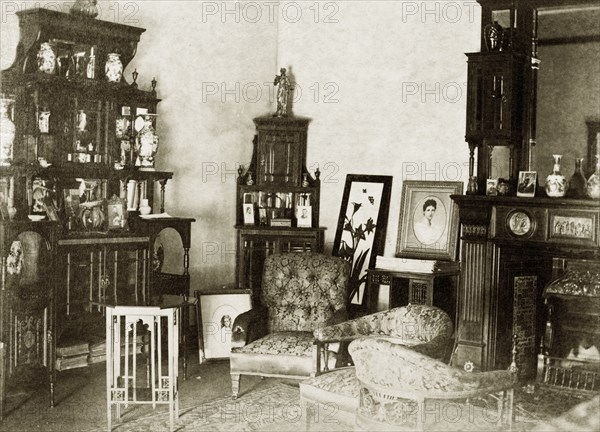 Domestic interior at 'Wyalla'. The corner of a heavily furnished drawing room at 'Wyalla', decorated with elaborate display cabinets and a large carved wooden fireplace. Toowoomba, Australia, circa 1905. Toowoomba, Queensland, Australia, Australia, Oceania.