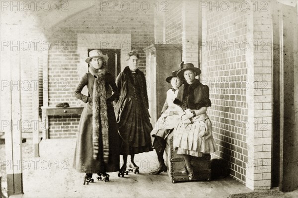 Rollerskating at 'Wyalla'. Prunella (Prue) Brodribb and other members of the Brodribb family pose for the camera on the veranda at 'Wyalla'. Prue, distinguished by her long fur scarf, and her nearest companion wear rollerskates. Toowoomba, Australia, circa 1905. Toowoomba, Queensland, Australia, Australia, Oceania.