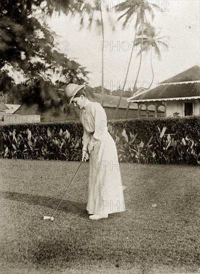 Playing golf, Ross Island. Anne Wood plays golf in the garden of a colonial house. Ross Island, India, circa 1905. Ross Island, Andaman and Nicobar Islands, India, Southern Asia, Asia.