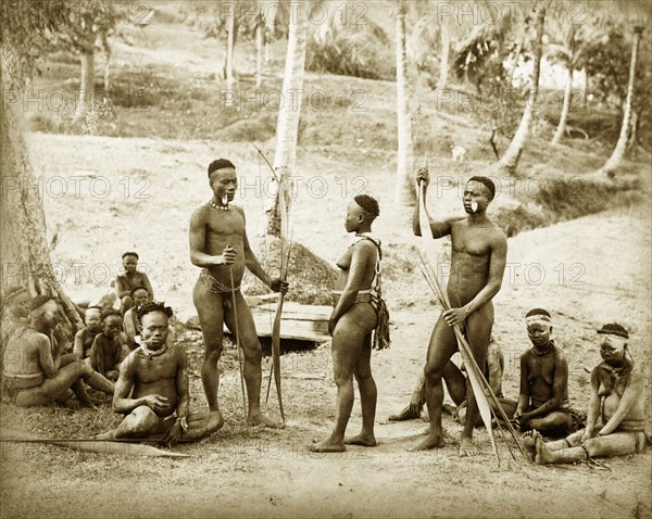 Andaman Islanders. Outdoors portrait of a group of Andaman Islanders. Two men holding staffs and bows and arrows are surrounded by other men, women and children, some of whom smoke clay pipes. Nearly all are naked: most wear some form of beaded ornamentation. Andaman Islands, India, circa 1900., Andaman and Nicobar Islands, India, Southern Asia, Asia.