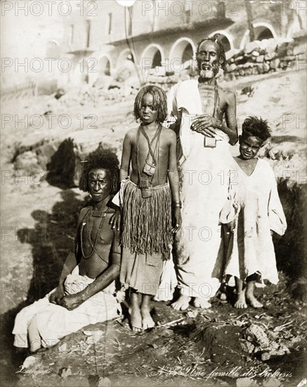 Portrait of a Bischarin family. Group portrait of two adult men and two children, possibly boys. The older man and older child are both wearing leather amulet holders strung around their neck. Probably Sudan, North Africa, circa 1885. Sudan, Eastern Africa, Africa.
