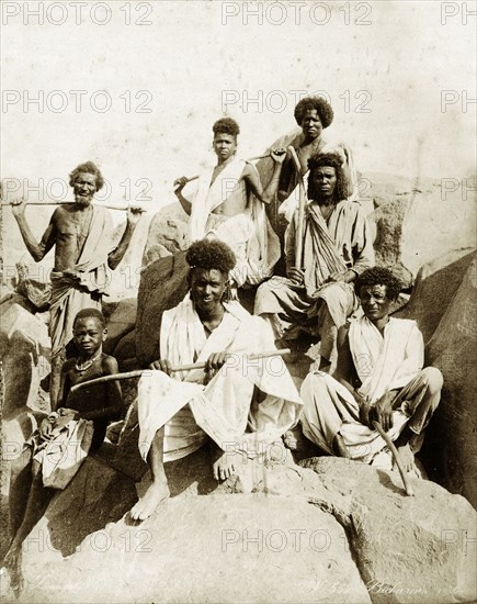 A group of Bisharin people. Group portrait of seven Bisharin people posed on boulders. Probably Sudan, North Africa, circa 1885. Sudan, Eastern Africa, Africa.