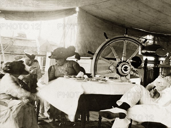 Taking tea aboard RIMS 'Minto'. Mrs and Miss McAlpin take tea with senior naval officers aboard RIMS 'Minto', which is harboured at Bombay. Bombay (Mumbai), India, circa 1900. Mumbai, Maharashtra, India, Southern Asia, Asia.