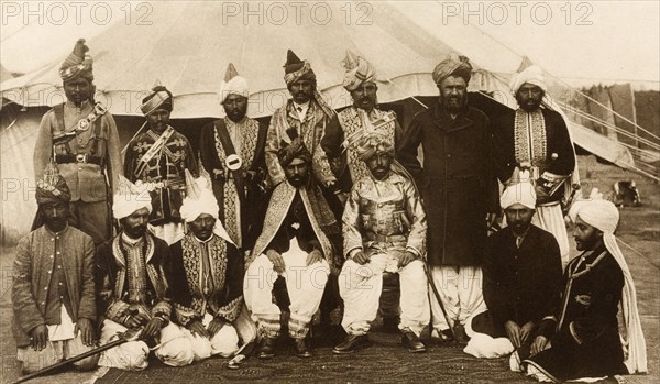 Baluchstan chiefs at the Coronation Durbar. Outdoors group portrait of Mir Mahmud Khan, Khan of Kalat (seated on chair, left) and Mir Kamal Khan, Jam of Las Bela (seated on chair, right), with other chiefs from Baluchistan, at the Coronation Durbar. Delhi, India, January 1903. Delhi, Delhi, India, Southern Asia, Asia.