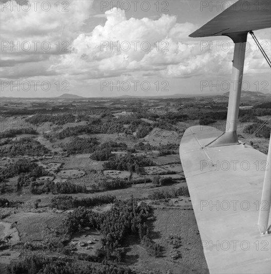 Kikuyu Reserve from the air. Aerial view taken from a Kenya Police Reserve (KPR) aircraft showing the patchwork of densely wooded terrain covering the slopes of the Kikuyu Reserve near Mount Kenya. Several Kikuyu villages are visible in clearings amongst the trees. Rift Valley, Kenya, 30 October 1952., Rift Valley, Kenya, Eastern Africa, Africa.