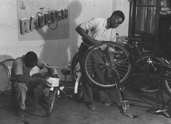 Kassam Kanji's workshop'. Two men at work repairing bicycles of all sizes in a workshop identified as 'Kassam Kanji's'. Kenya, 22 November 1952. Kenya, Eastern Africa, Africa.
