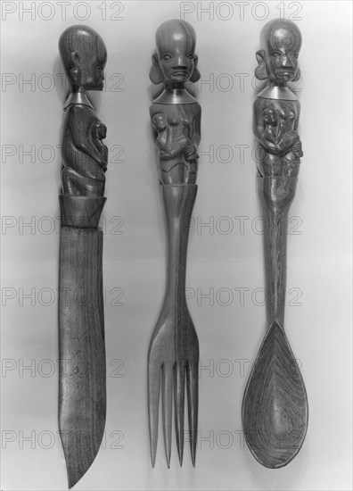 Carved wooden cutlery, Kenya. Three pieces of decorative wooden cutlery, including a knife, fork and spoon. The handles are intricately carved with the figure of a mother holding a baby. Kenya, 5 December 1952. Kenya, Eastern Africa, Africa.