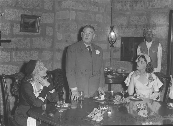 Genniclift-Thompson wedding. A middle-aged man stands to deliver his speech to the table at the Genniclift-Thompson wedding. Kenya, 13 December 1952. Kenya, Eastern Africa, Africa.