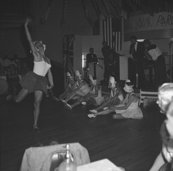A graceful leap. One of several men dressed as ballerinas leaps gracefully across the floor as the group perform a skit at the cabaret of a square dance party. Kenya, 18 December 1952. Kenya, Eastern Africa, Africa.