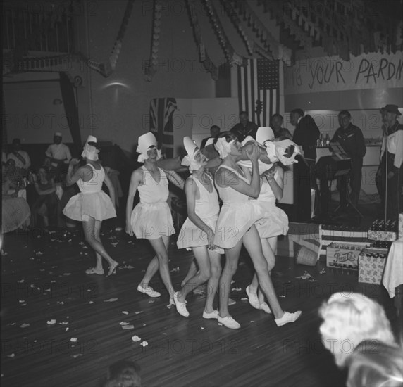 Men in tutus. A group of men bare their legs in tutus as they perform a skit as male ballerinas at the cabaret of a square dance party. Kenya, 18 December 1952. Kenya, Eastern Africa, Africa.