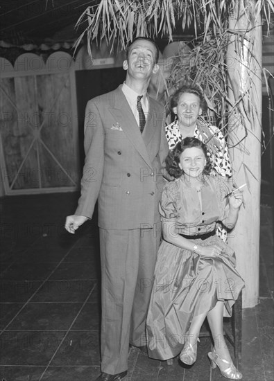 Guests at a Christmas party. Mr and Mrs Morris pose for the camera with Mrs Holmes at a Christmas party being held at the Forest Inn. Kenya, 25 December 1952. Kenya, Eastern Africa, Africa.
