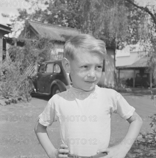 Dusty Miller's son. Portrait of one of Dusty Miller's two sons, standing hands on hips outside the family home. Kenya, 28 December 1952. Kenya, Eastern Africa, Africa.