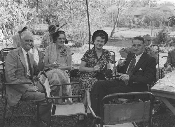 Guests at the Allen-Winter wedding. Guests at the Wendy Allen-Dudley Winter wedding relax with glasses of champagne in a sunny garden. Kenya, 30 December 1952. Kenya, Eastern Africa, Africa.