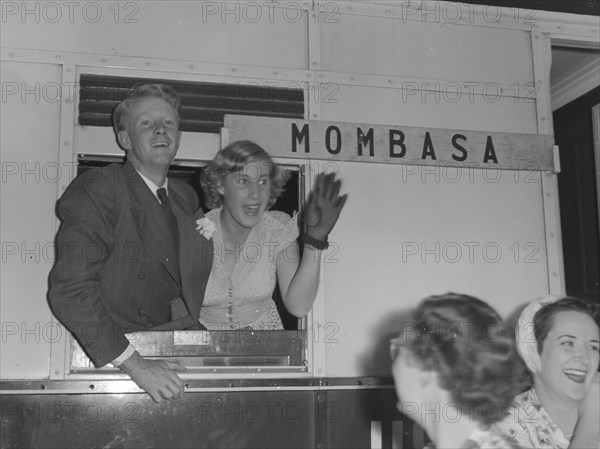 Wedding couple on a train. Jeremy and Jane, guests at the Wendy Allen-Dudley Winter wedding, wave farewell to friends from a train headed for Mombasa. Kenya, 30 December 1952. Kenya, Eastern Africa, Africa.