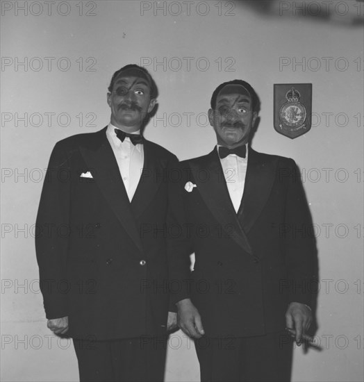 Eric Mathers and Cecil'. Two suited men identified as 'Eric Mathers and Cecil' pose for the camera wearing identical fancy dress masks at the Archer's New Year's Party. Kenya, 31 December 1952. Kenya, Eastern Africa, Africa.