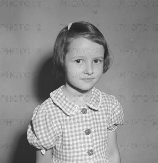 Burt Condon's daughter. A European child identified as 'Burt Condon's girl', poses shyly for the camera wearing a gingham dress. Kenya, 2 January 1953. Kenya, Eastern Africa, Africa.