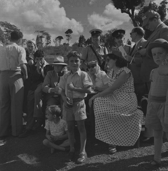 Soap box derby. A group of 'officials' wait patiently at the finish line for contestants in a soap box derby race. Kenya, 3 January 1953. Kenya, Eastern Africa, Africa.