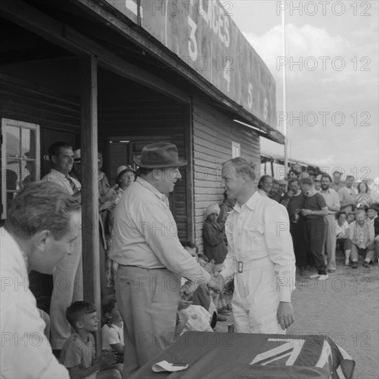 Handshake at the Nakuru Races. A man in white overalls shakes hands as he receives an award at a Nakuru Races prizegiving ceremony. Nakuru, Kenya, 15 September 1957. Nakuru, Rift Valley, Kenya, Eastern Africa, Africa.